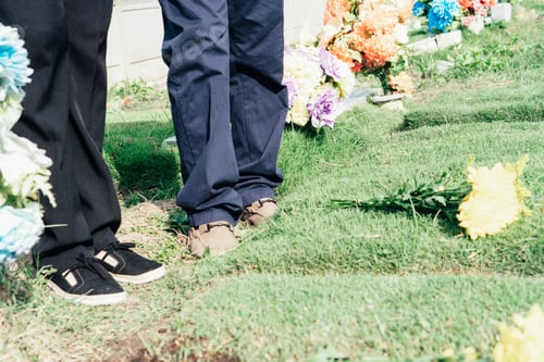 Preview: People commemorating at cemetery with colorful flowers