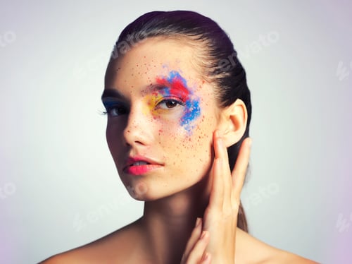 Preview: Studio shot of an attractive young woman posing with her face brightly painted