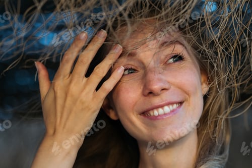 Preview: Close-up portrait of young caucasian woman smiling and looking sideways.