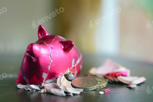 Preview: Smashed piggy bank with pounds on table.