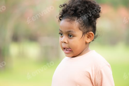 Preview: Happy young girl smiling in a green park during summer, portraying childhood joy and innocence
