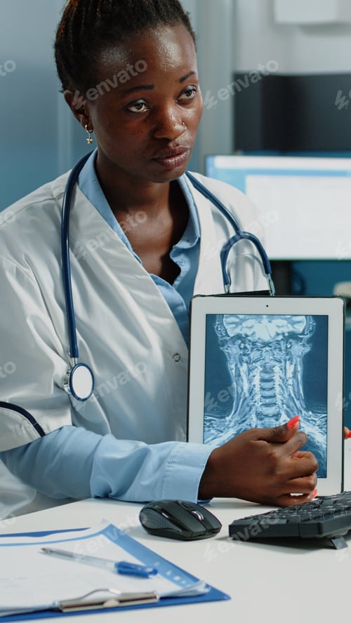 Preview: Medical specialist pointing at x ray scan on tablet for checkup