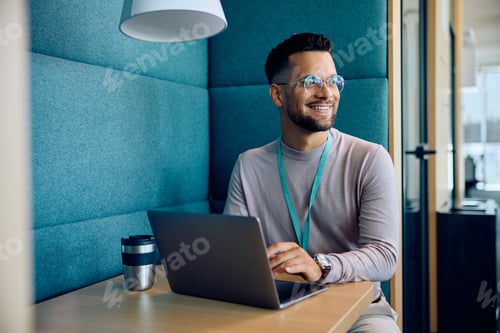 Preview: Young happy entrepreneur using laptop at office cafeteria.