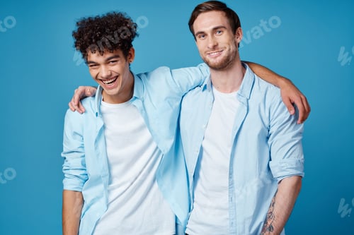 Preview: guy with curly hair in a shirt and a t-shirt on a blue background and a young man friends fun