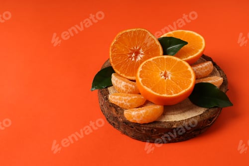Preview: Board with mandarins with leaves on orange background