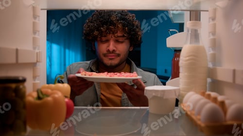Preview: View inside from refrigerator Indian sly man with curly hair open fridge at night evening in kitchen