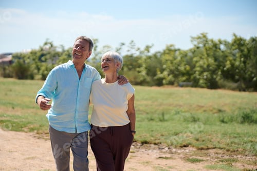 Preview: Happy senior couple walking and smiling in a park