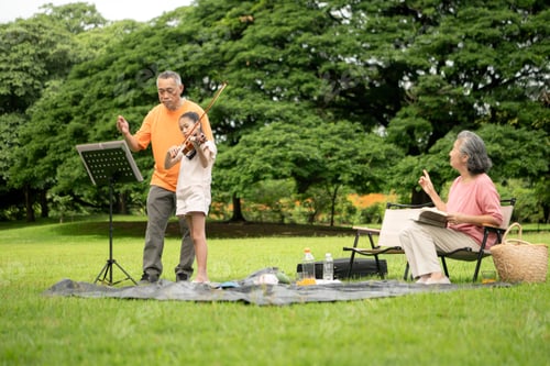 Preview: Happy Asian grandparents enjoying a picnic with their granddaughter in a green park
