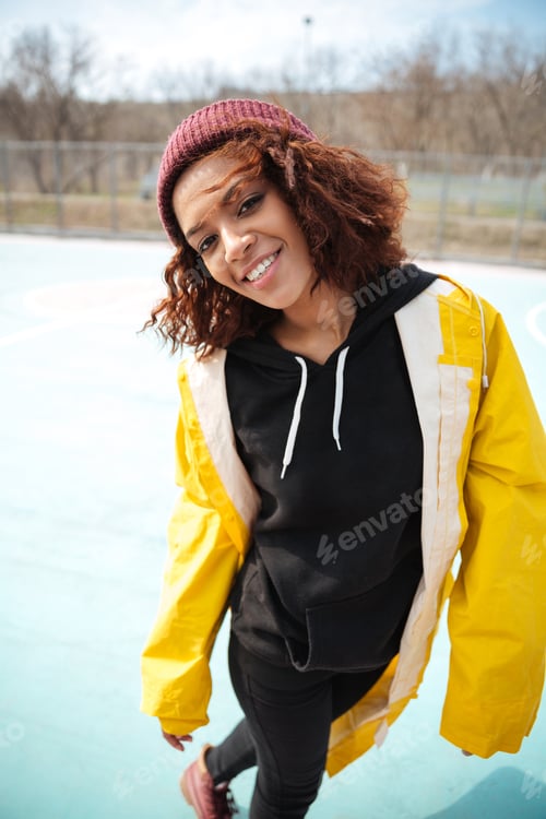 Preview: Happy african curly young woman wearing yellow coat