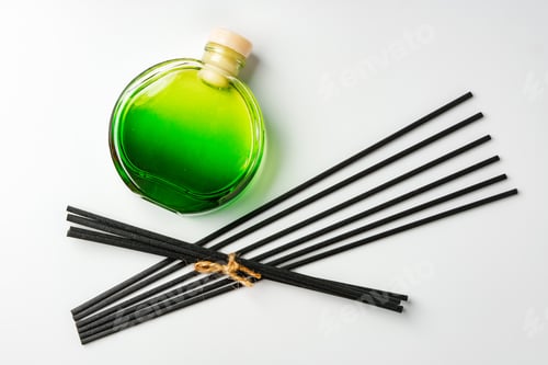 Preview: A minimalist display of essential oil and black diffuser sticks on a clean white background