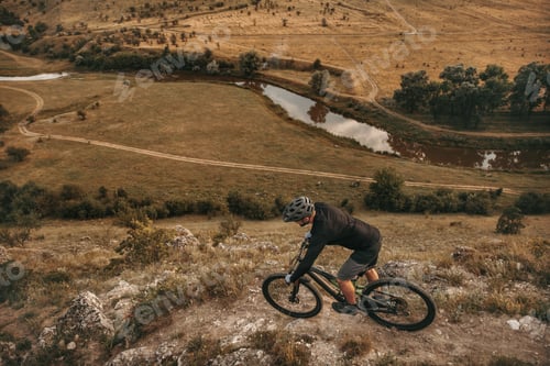 Preview: Unrecognizable man riding bike in mountains