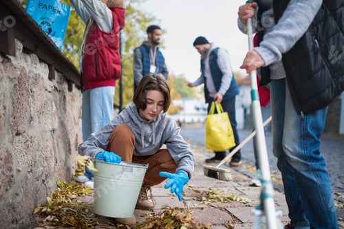 Preview: Diverse group of happy volunteers cleaning up street, community service concept