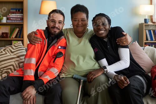 Preview: Middle Aged Black Woman Sitting between Paramedics Smiling and Embracing