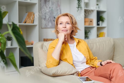 Preview: Blond pensive woman relaxing on couch in home environment while enjoying break