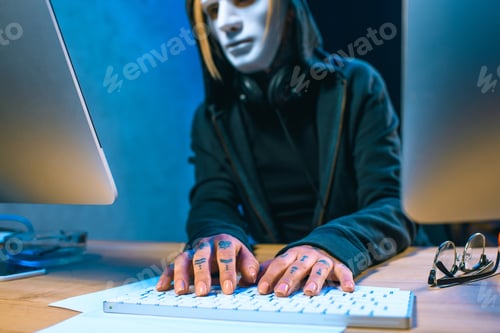 Vista previa: close-up shot of masked female hacker with tattoos on hands developing malware
