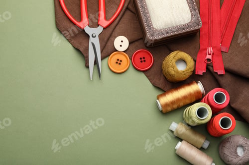 Preview: Different sewing supplies on olive background, flat lay. Space for text