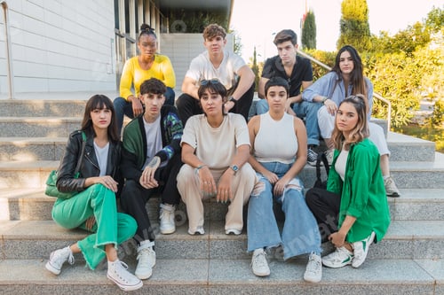 Preview: Group of diverse friends sitting on stairs of building in daylight