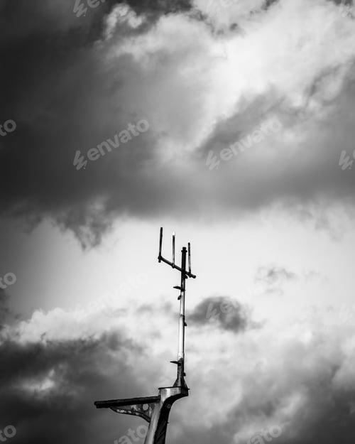 Preview: Greyscale shot of an antenna with dark clouds background