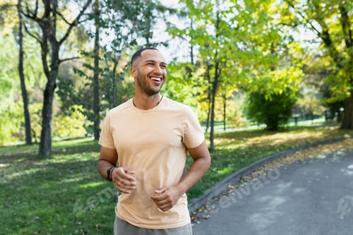Preview: Cheerful and successful hispanic man jogging in the park, man running on a sunny day, smiling and