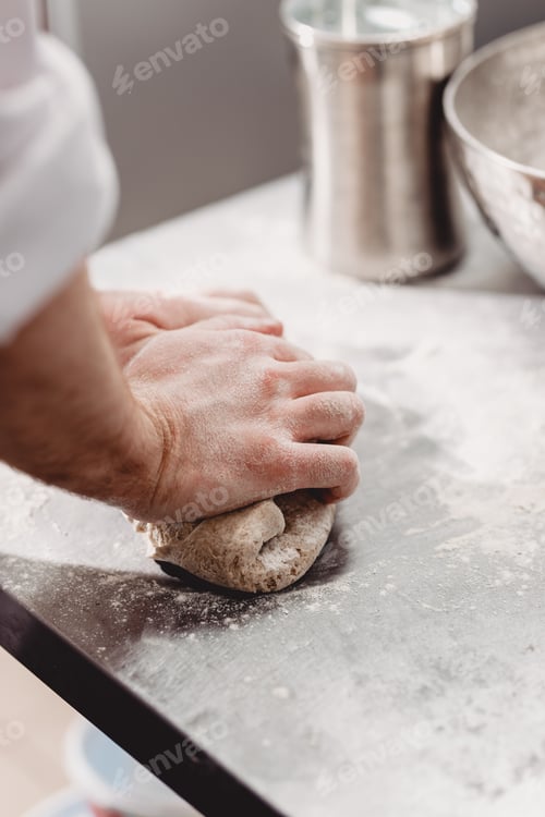 Preview: Baker punchs down the dough in the kitchen in the bakery