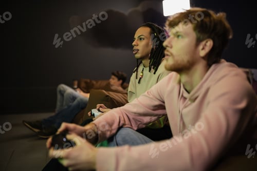 Preview: KYIV, UKRAINE - FEBRUARY 13, 2023: Multiracial man playing video game with blurred friend in gaming