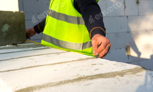 Preview: Construction worker at construction site measures the length of the window opening