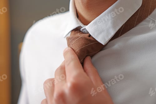 Preview: Man tying stylish necktie at home, closeup