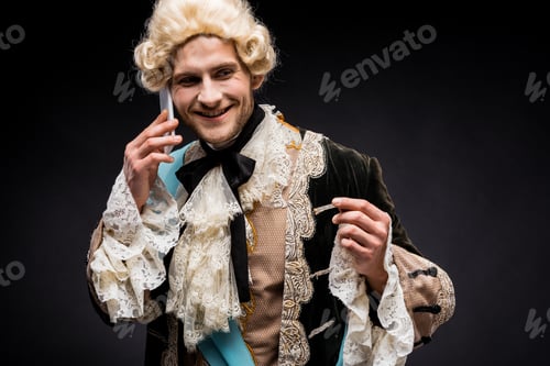 Preview: happy victorian man in wig smiling while talking on smartphone on black