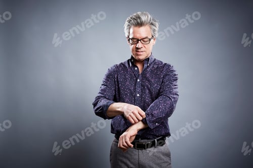 Preview: Studio portrait of mature businessman rolling up his sleeves