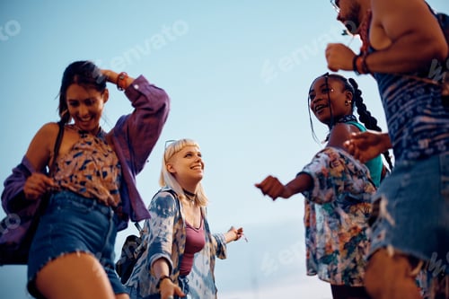Preview: Below view of young happy people dancing and having fun on summer music festival.