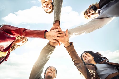 Preview: Multiracial happy young people stacking hands outside