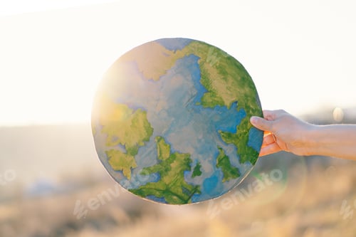 Preview: Woman holding planet in hands against green spring background. Earth day
