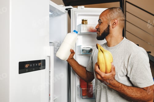 Preview: African american man taking food from a fridge in his house