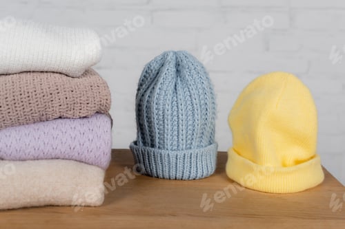 Preview: Warm hats and sweaters on wooden table on white background