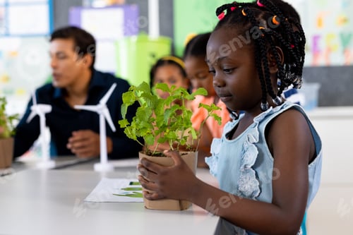 Preview: Happy african american girl with plant in ecology class at elementary school