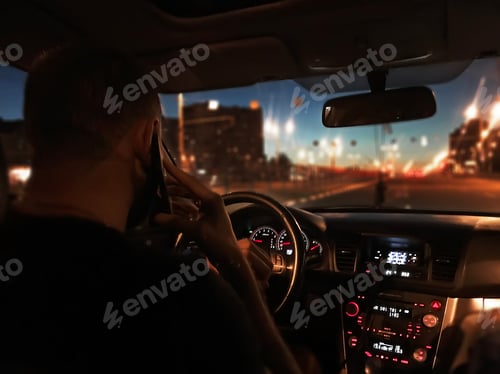 Preview: Young man using mobile phone and driving a car through the night city road