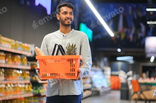 Preview: Portrait of handsome young Indian man standing at grocery shop or supermarket. Selective Focus.