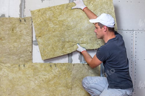 Preview: Worker insulating a room wall with mineral rock wool thermal insulation.