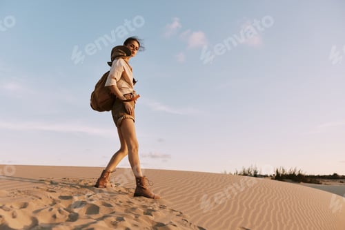 Preview: Exploring the vast desert A woman trekking through sandy dunes with a backpack, seeking adventure