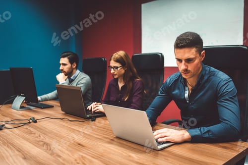 Preview: Colleagues at a start up company working on their laptops in colorful red and blue walls in the