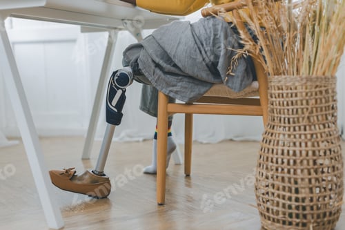 Preview: Woman with prosthetic leg sitting in chair in living room at home. Relaxed,