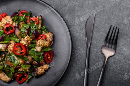 Preview: A salad of baked aubergine, sweet pepper, garlic, zucchini and parsley in a black plate