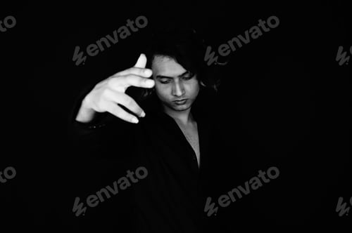 Preview: Grayscale shot of a serious young South Asian guy from India posing on a black background