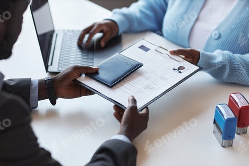 Preview: Hands of young African American male applicant passing documents and passport