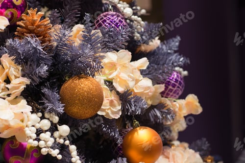 Preview: Christmas tree with golden and violet luxury balls on blurred background in mall.