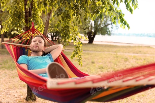 Preview: Handsome young man resting in hammock outdoors
