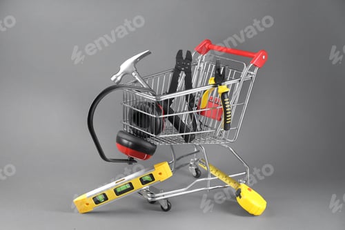 Preview: Small shopping cart with set of construction tools and headphones on grey background