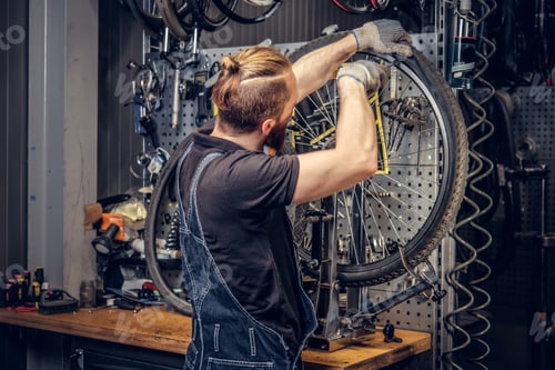 Preview: Mechanic repairing bicycle wheel tire in a workshop.