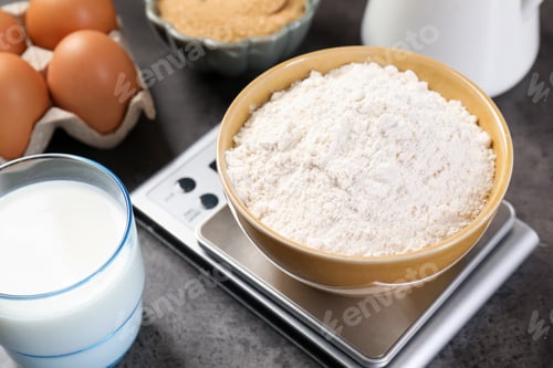 Preview: Digital kitchen scale with bowl of flour and other products on grey table, closeup