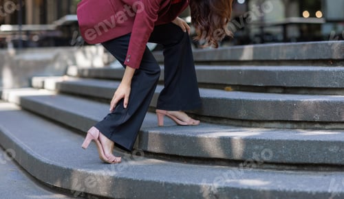 Preview: Businesswoman experiencing leg pain walking up stairs